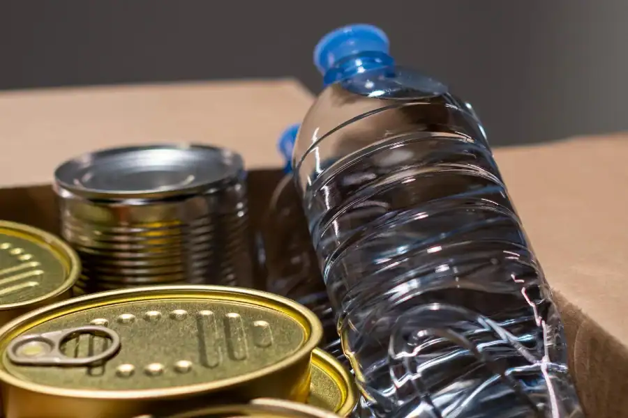 Canned food and bottled water packed for a storm shelter emergency kit