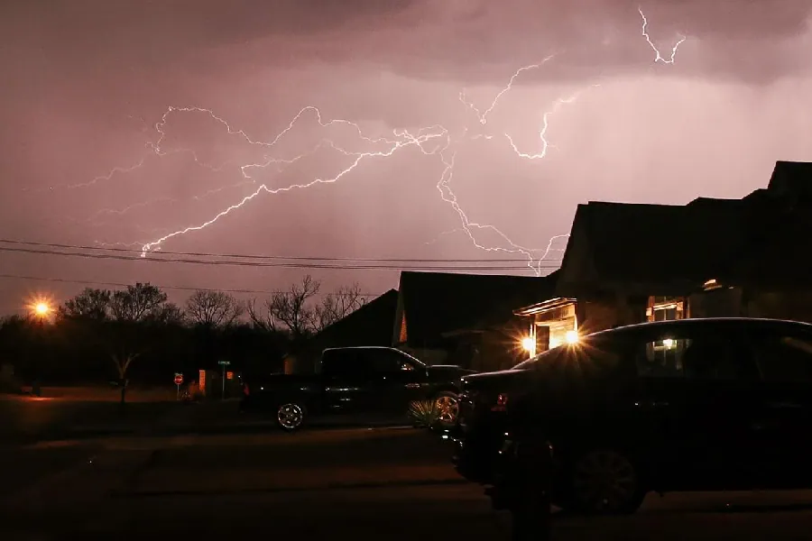Lightning over homes during severe weather at night