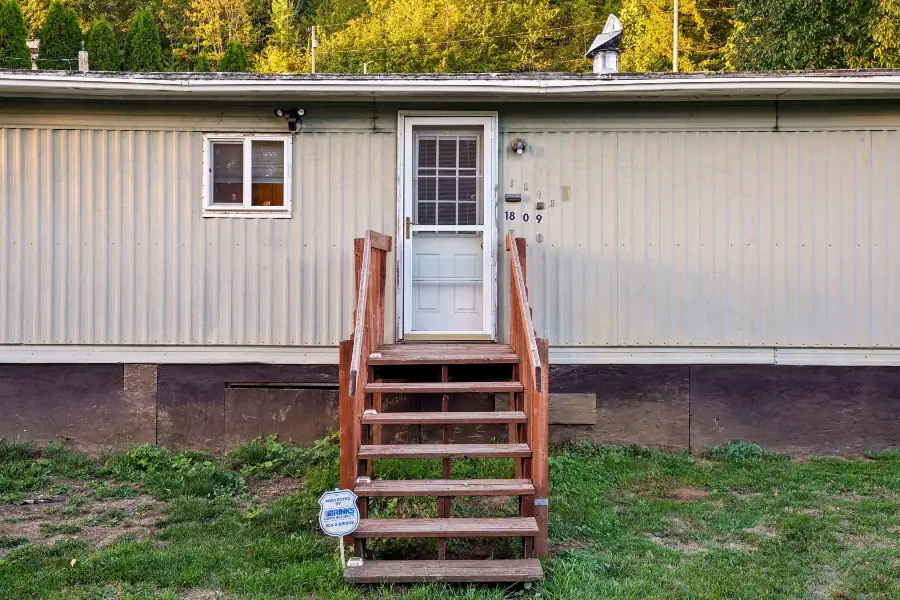 Residential mobile home with front steps and grassy yard